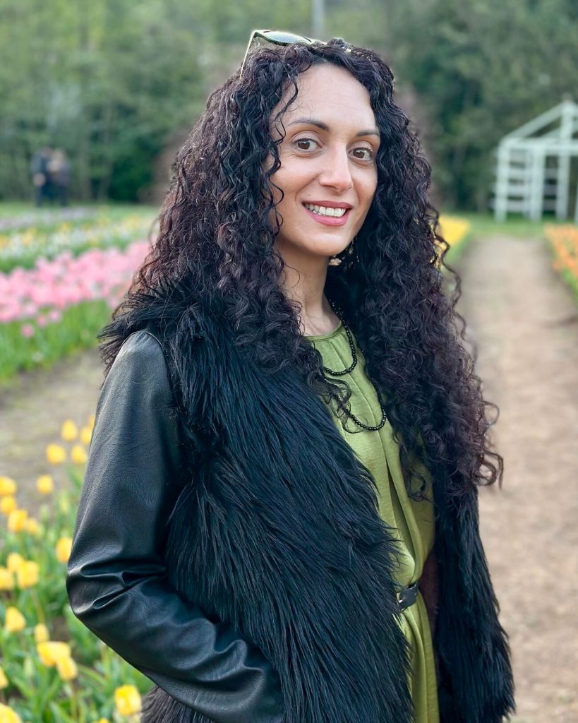 Sha, hard gel nail educator and founder of Sha Nails, smiling in a tulip field